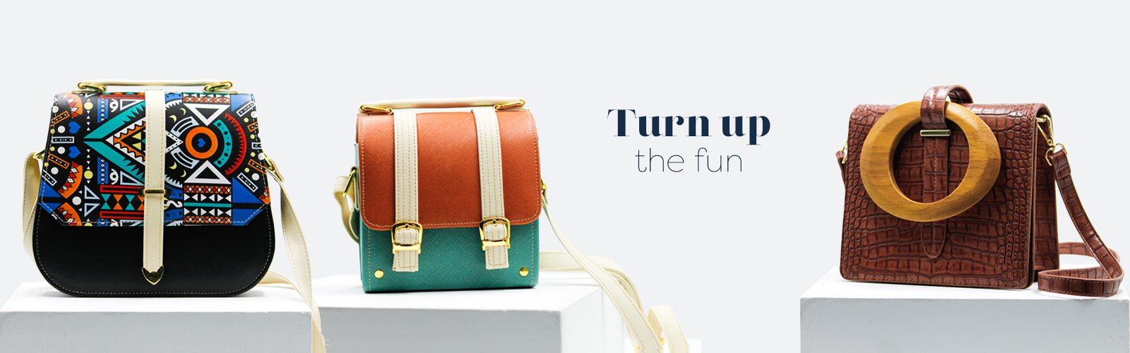 Product shot of multicolour aztec bag, orange & teal box bag and brick-red croc embossed bag with the text "Turn up the fun"